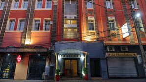 A hotel with a prominent entrance, a sign reading "TANA HOTEL," and a storefront named "La Chocolatiere" adjacent to it. - Tana Hôtel (Antananarivo)