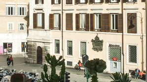 Un immeuble à plusieurs étages, doté d’une architecture traditionnelle, avec des portes en arc de cercle et une série de fenêtres équipées de volets.