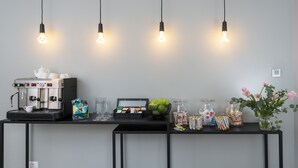 Un espace dédié au café, comprenant une machine à café, une théière, ainsi qu’un assortiment de dosettes de café et de collations.