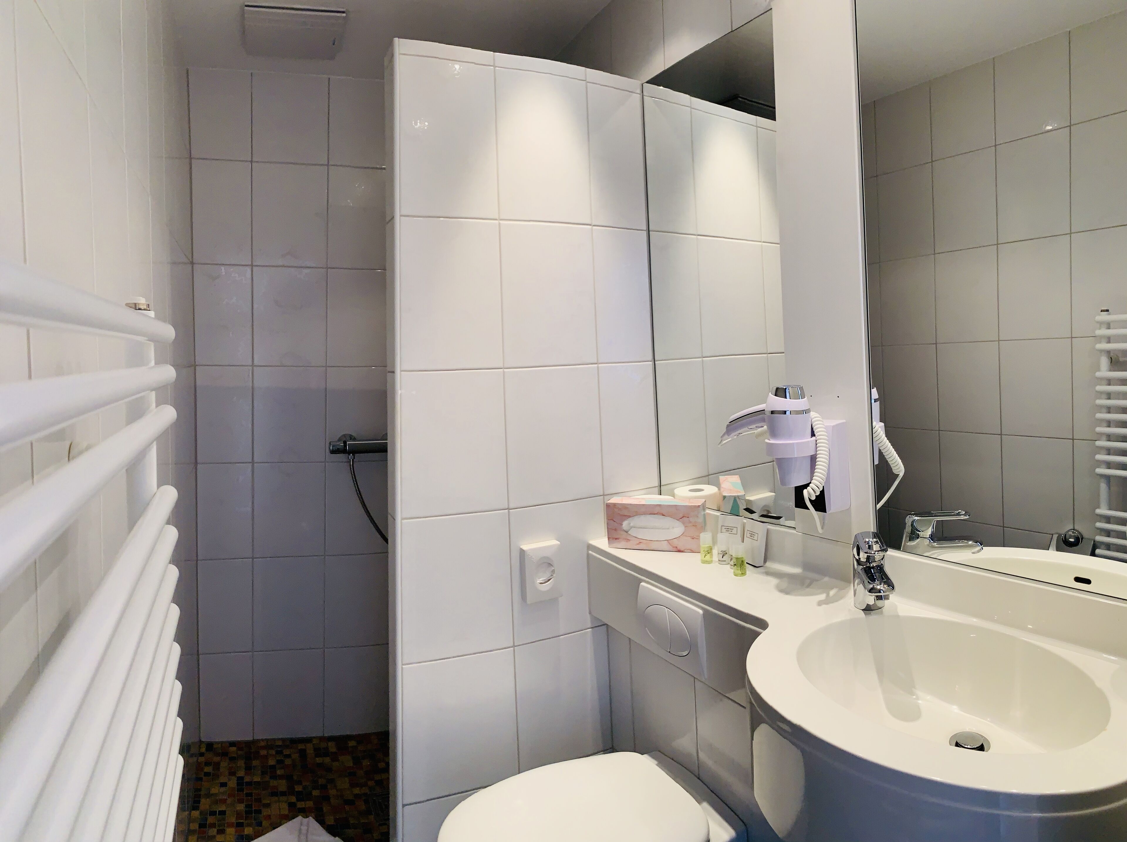 A modern bathroom with a white sink, toilet, and shower area.