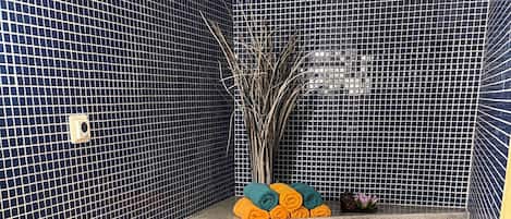 Un baño con pared de azulejos azules, un lavamanos con grifo y un lavabo.