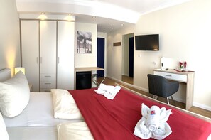 A hotel room with a bed, a desk, a chair, a wardrobe, and a television. - Aparthotel kleine Perle (Cuxhaven)