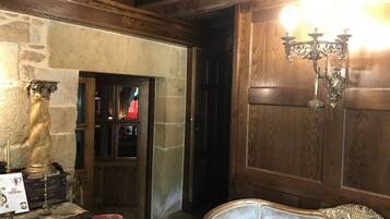 Una habitación con pared de piedra, puerta de madera y un candelabro.