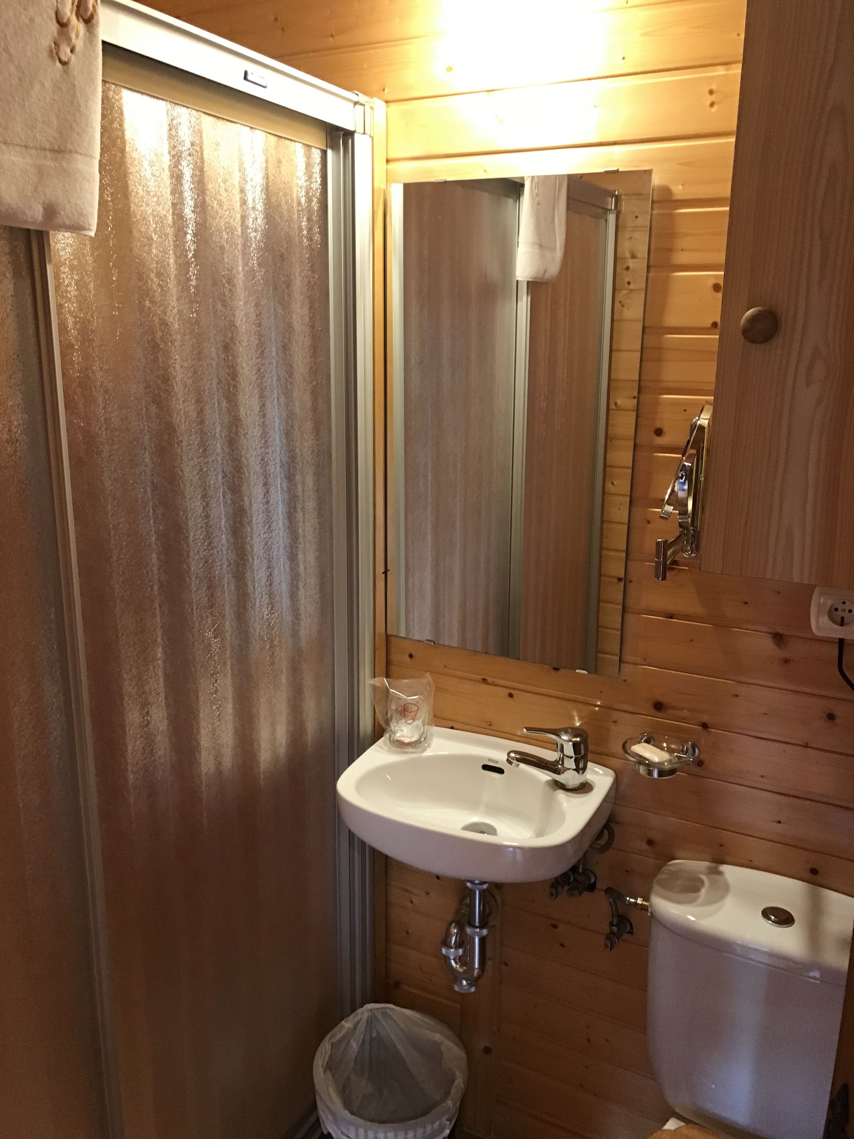 A wooden interior bathroom with a white sink, mirror, and toilet.