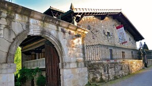 A stone building with an arched entrance, a wooden door, and a balcony. - Hotel Palacio de Trasvilla (Villafufre)