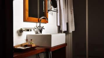 Un baño con lavamanos blanco, tocador de madera, espejo con marco de madera y cortina de ducha.