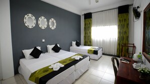 Une chambre d’hôtel avec deux lits, une table à manger et un ventilateur de plafond.