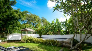Un jardin avec un mur blanc, un petit étang et un kiosque.