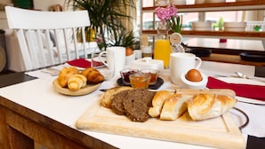 Ein Frühstückstisch mit Croissants, Brot und Saft.