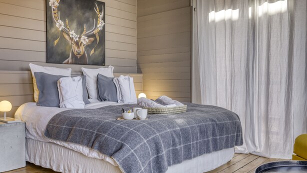 Ein Schlafzimmer mit einem großen Bett, einem Nachttisch mit Lampe, einem Gemälde an der Wand und einem Fenster mit Vorhängen.