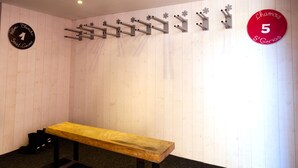 Ein Zimmer mit einer hölzernen Bank, einem Kleiderhaken und zwei Schildern an der Wand.