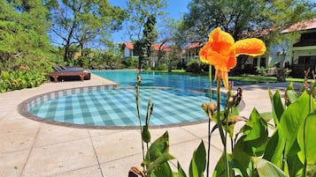 Relax by the serene pool surrounded by lush greenery and vibrant flowers.