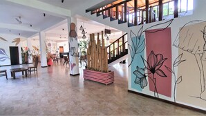 Un vestíbulo amplio con techo alto, una escalera y una pared decorada con motivos florales.