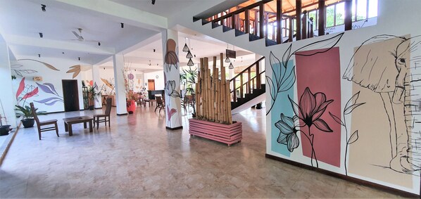 Un vestíbulo amplio con techo alto, una escalera y una pared decorada con motivos florales.