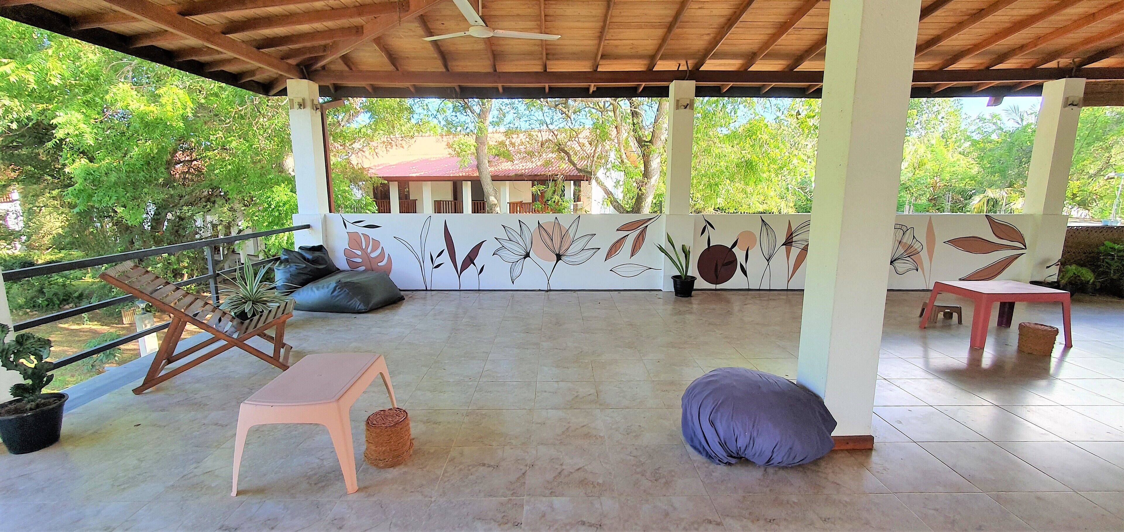 An outdoor covered patio with a ceiling fan, a wooden bench, a small table, and a cushion.