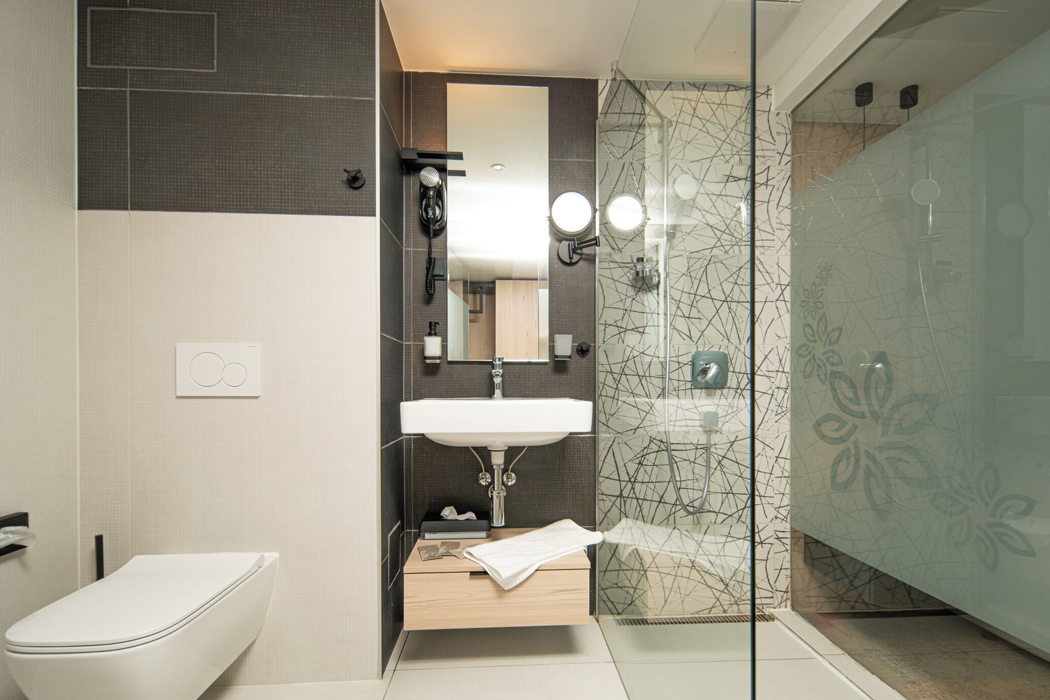 A modern bathroom with a toilet, sink, and glass shower enclosure.