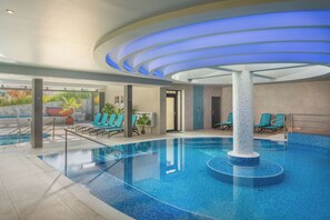Relax by the pool surrounded by lounge chairs and a seating area with a view of the outside.