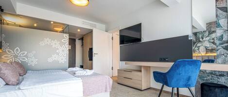 Ein modernes Schlafzimmer mit Bett, Schreibtisch, Stuhl und Fernseher.