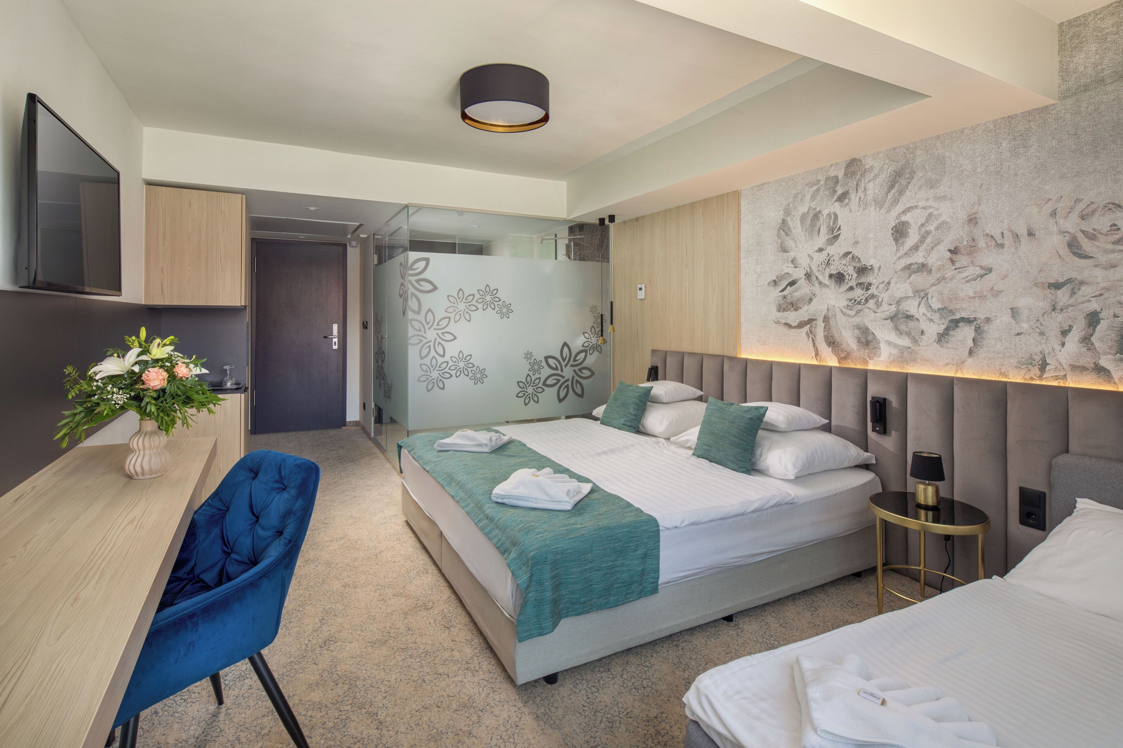 A modern hotel room with a bed, a desk, and a chair.