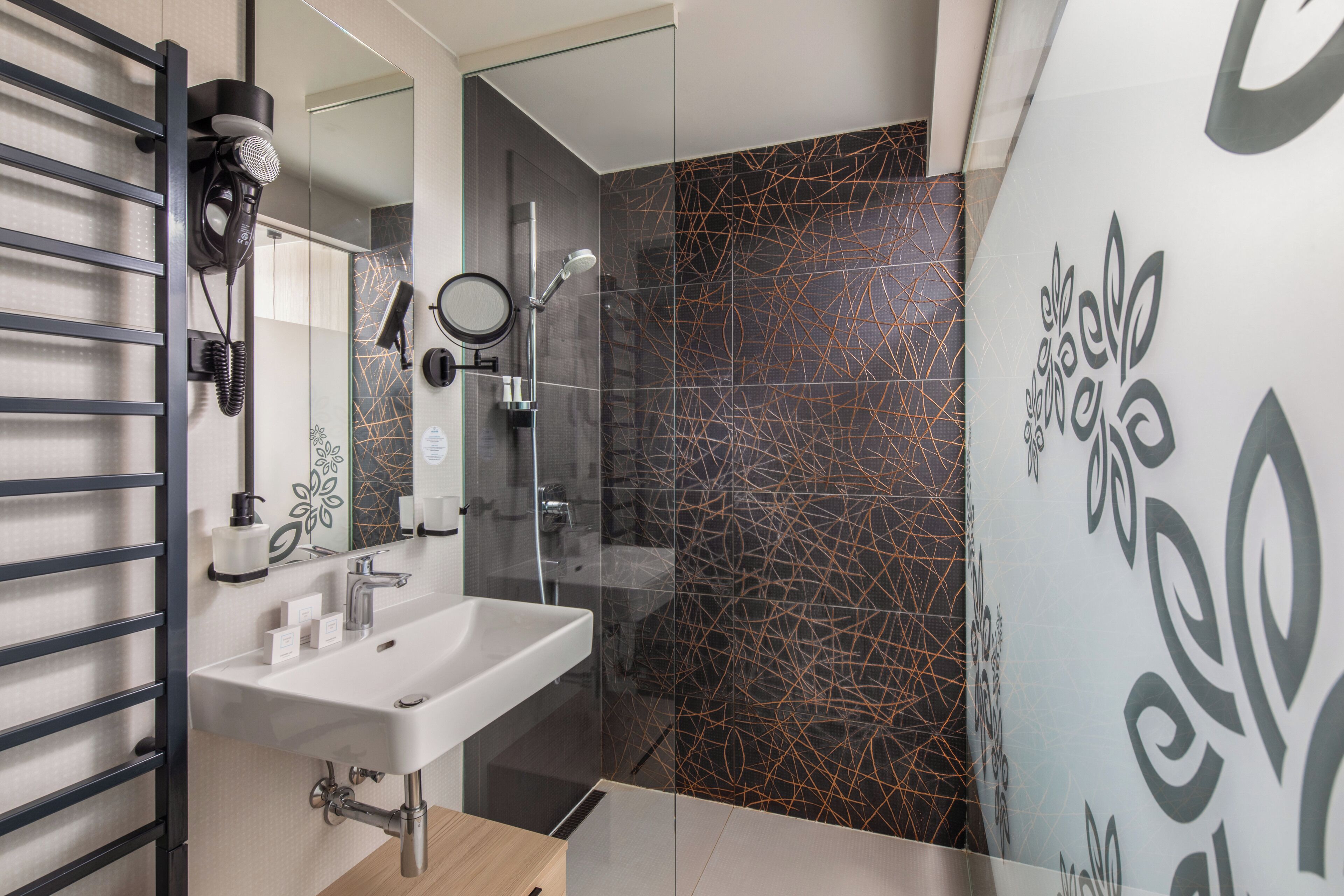 A modern bathroom with a white sink, a mirror, and a glass shower enclosure.