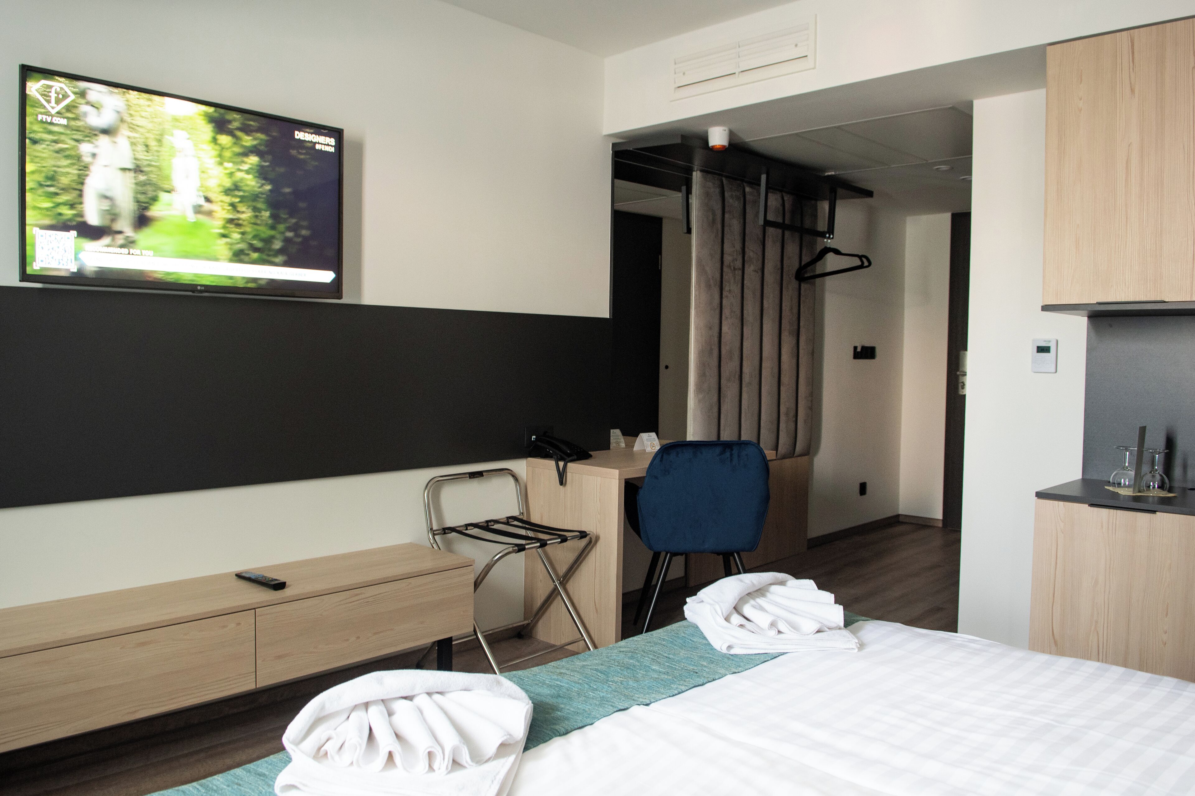 Une chambre d’hôtel comprenant un lit, un bureau, une chaise, une télévision et une armoire.