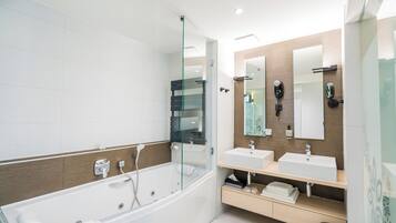 Un baño moderno con ducha de vidrio, dos lavamanos y tocador con espejo.