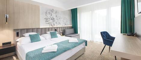 A modern hotel room with a large bed, a desk, and a chair.