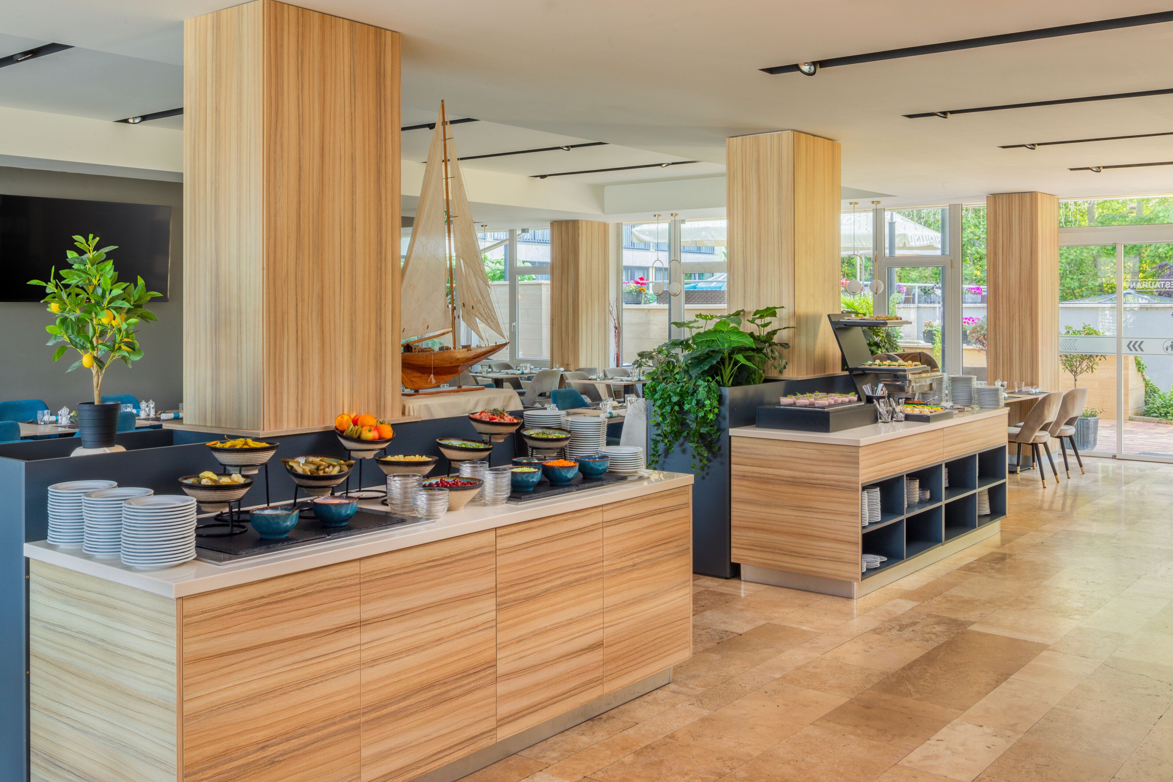 Una cocina moderna con armarios de madera, una isla central con comida y un ventanal grande.