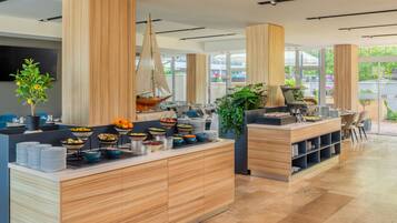 Una cocina moderna con armarios de madera, una isla central con comida y un ventanal grande.