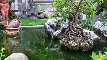 A pond with rocks, a statue, and a small tree.