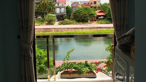 Vista desde un balcón con una fuente de agua, un letrero que dice “SEE YOU AGAIN”, y un vistazo de los edificios y la vegetación circundantes.