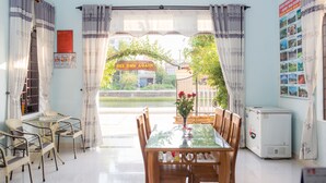 Un comedor con una mesa y sillas, un refrigerador y vistas a un jardín y edificios.