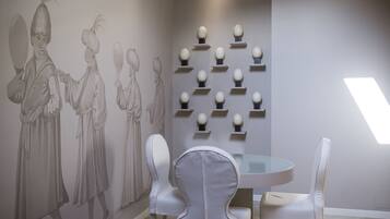 Un comedor con una mesa redonda, sillas blancas y una pared decorada con un mural.