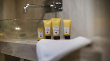 Three yellow tubes of Acqua Parma on a marble countertop in a bathroom.