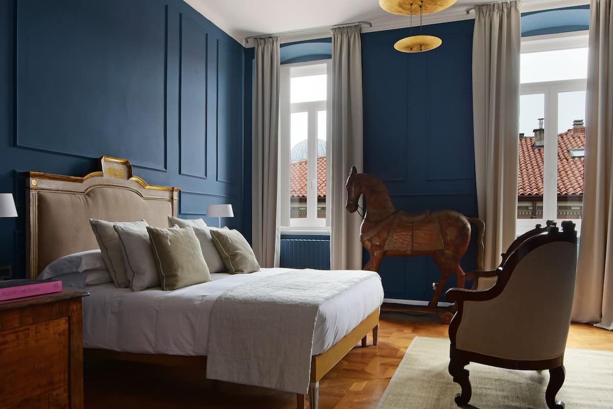 Quarto com cama, um balanço de madeira, uma cadeira e um lustre único.