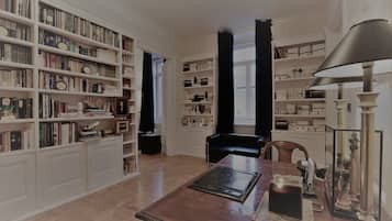 A spacious library with high ceilings and large windows, featuring extensive book collections and elegant furniture.