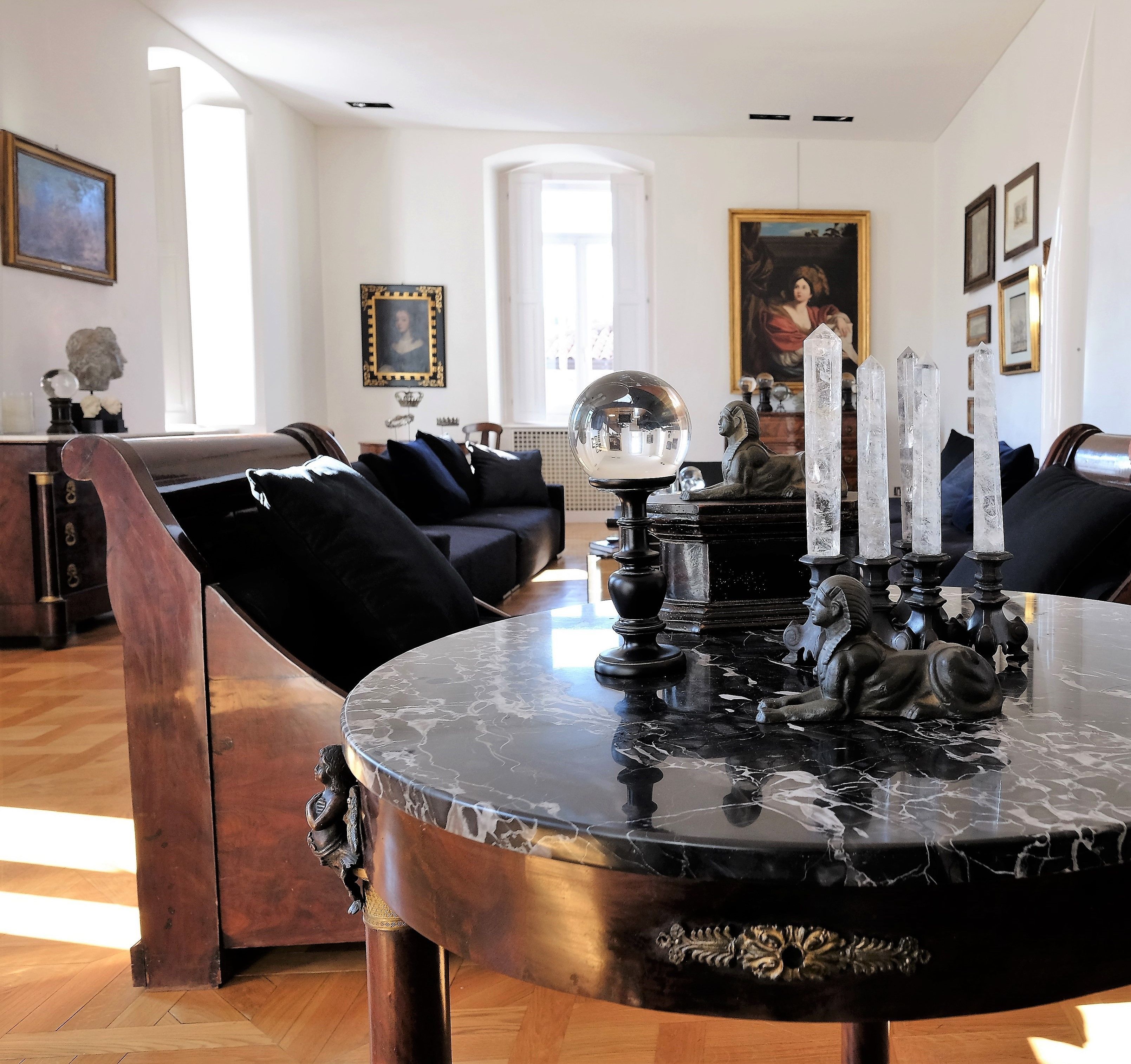 Un comedor con una mesa de mármol, sillas negras y candelabros de cristal.