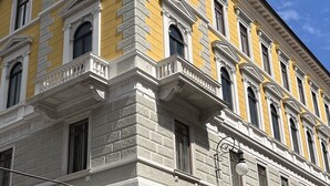 Un bâtiment jaune avec des bordures blanches et de nombreuses fenêtres.