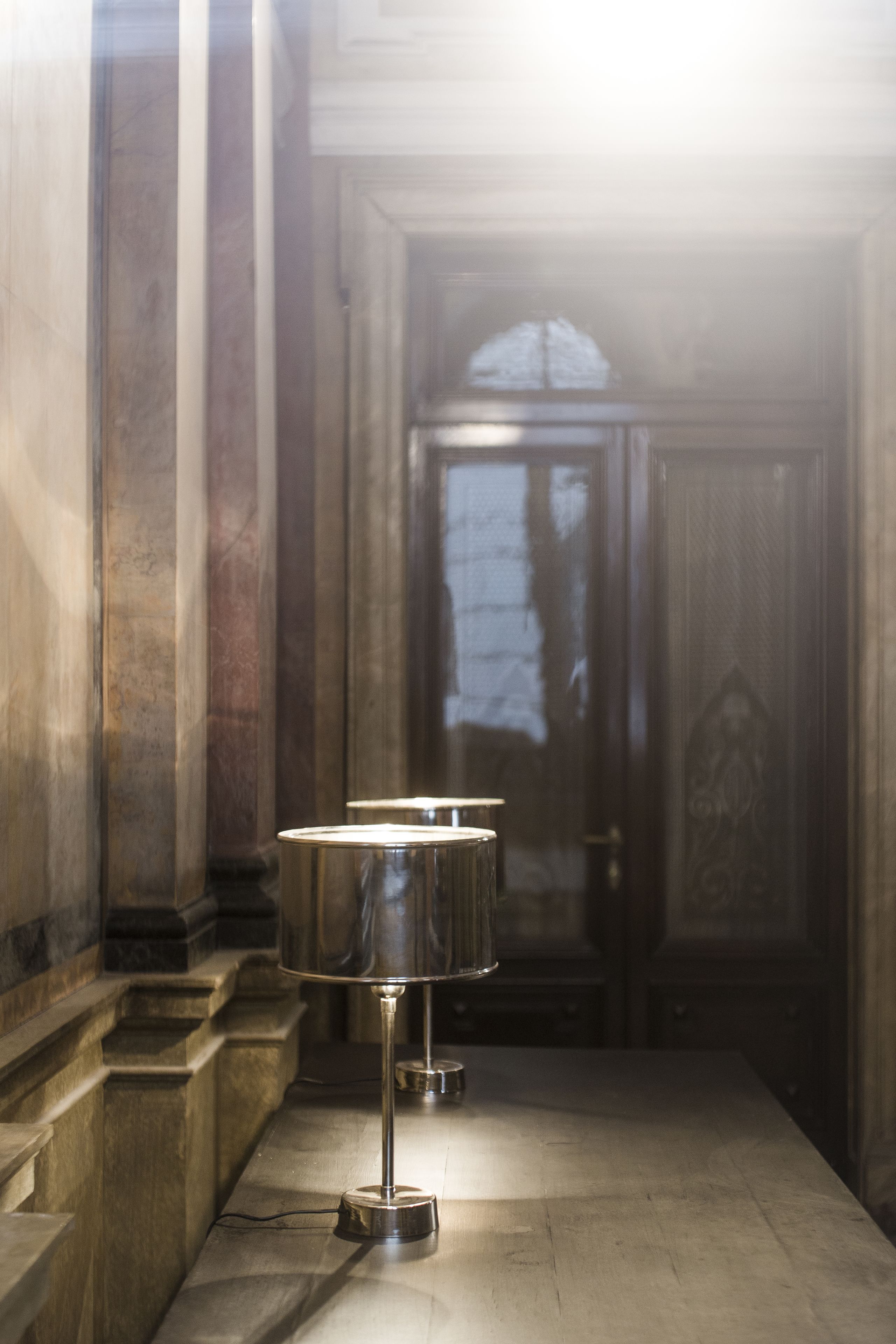 A corridor with a metal lamp post and a door with a window.