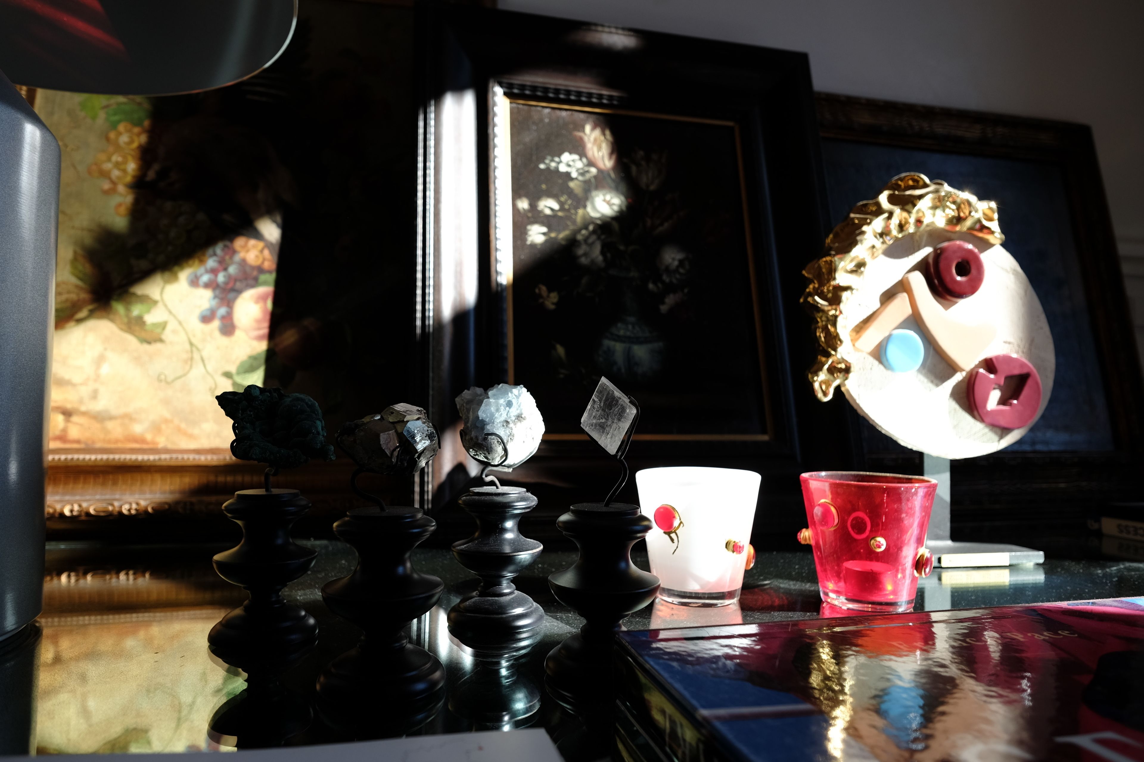 Una mesa con un juego de ajedrez, una taza roja y un espejo decorativo.