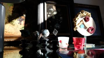 Una mesa con un juego de ajedrez, una taza roja y un espejo decorativo.