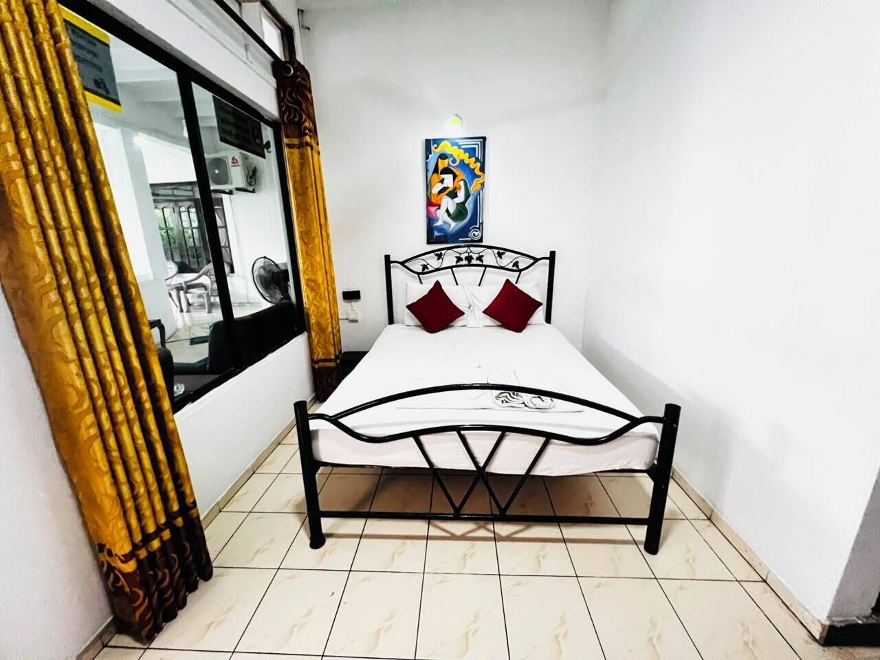 A small room with a bed, a window, and a wall-mounted picture.