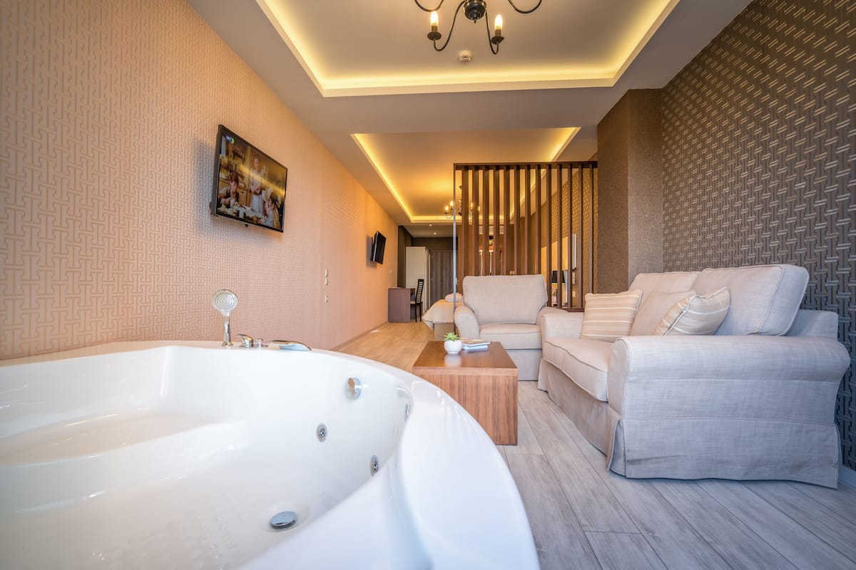 A modern bathroom with a large bathtub, a sofa, and a wooden coffee table.