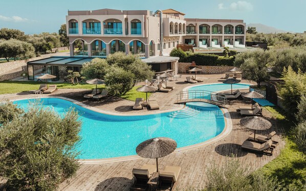 Un complexe hôtelier doté d’une grande piscine, de chaises longues et d’un bâtiment comportant de nombreux balcons.