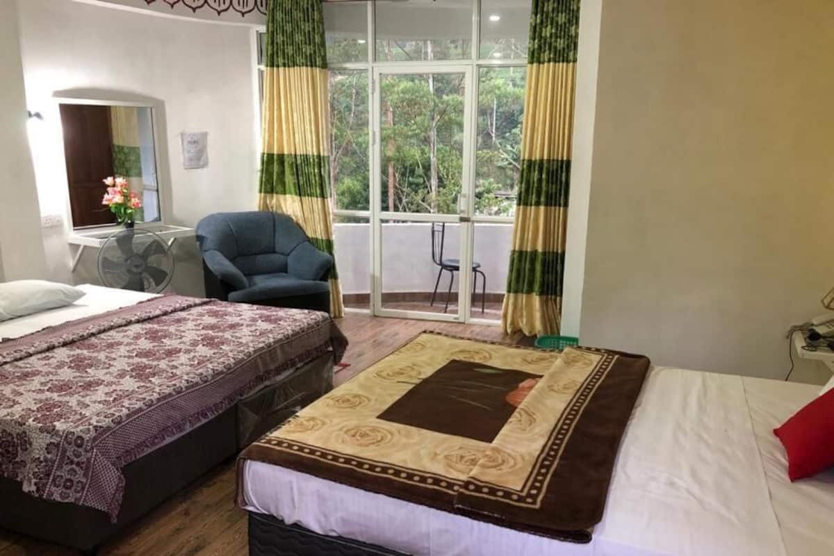 Een hotelkamer met twee bedden, een zithoek met een stoel, een klein tafeltje en een raam met gordijnen.