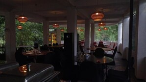 An indoor dining area with tables and chairs, hanging pendant lights, and a view of greenery outside. - White House Adam's Peak (Nallathanniya)