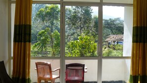 A room with a large window, two chairs, and a view of greenery outside. - White House Adam's Peak (Nallathanniya)
