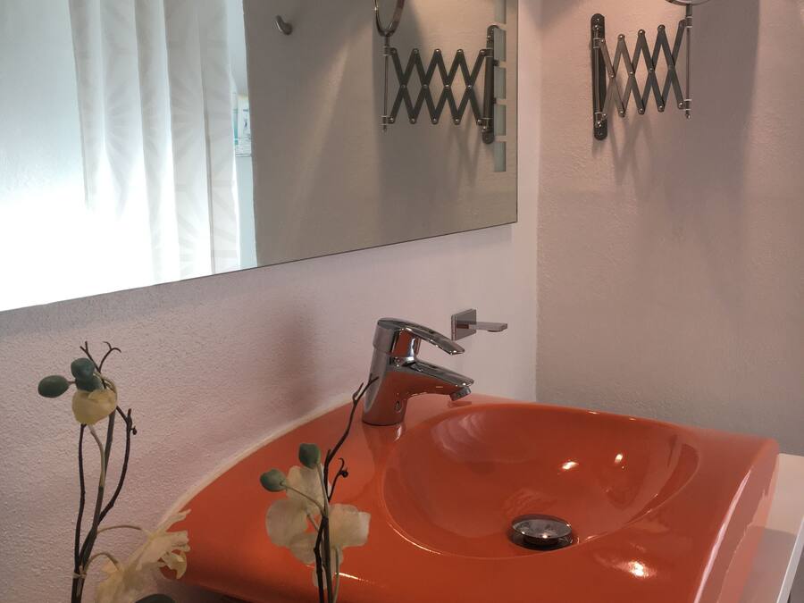 Een badkamer met een grote spiegel, een modern wastafelmeubel en een douchegordijn.