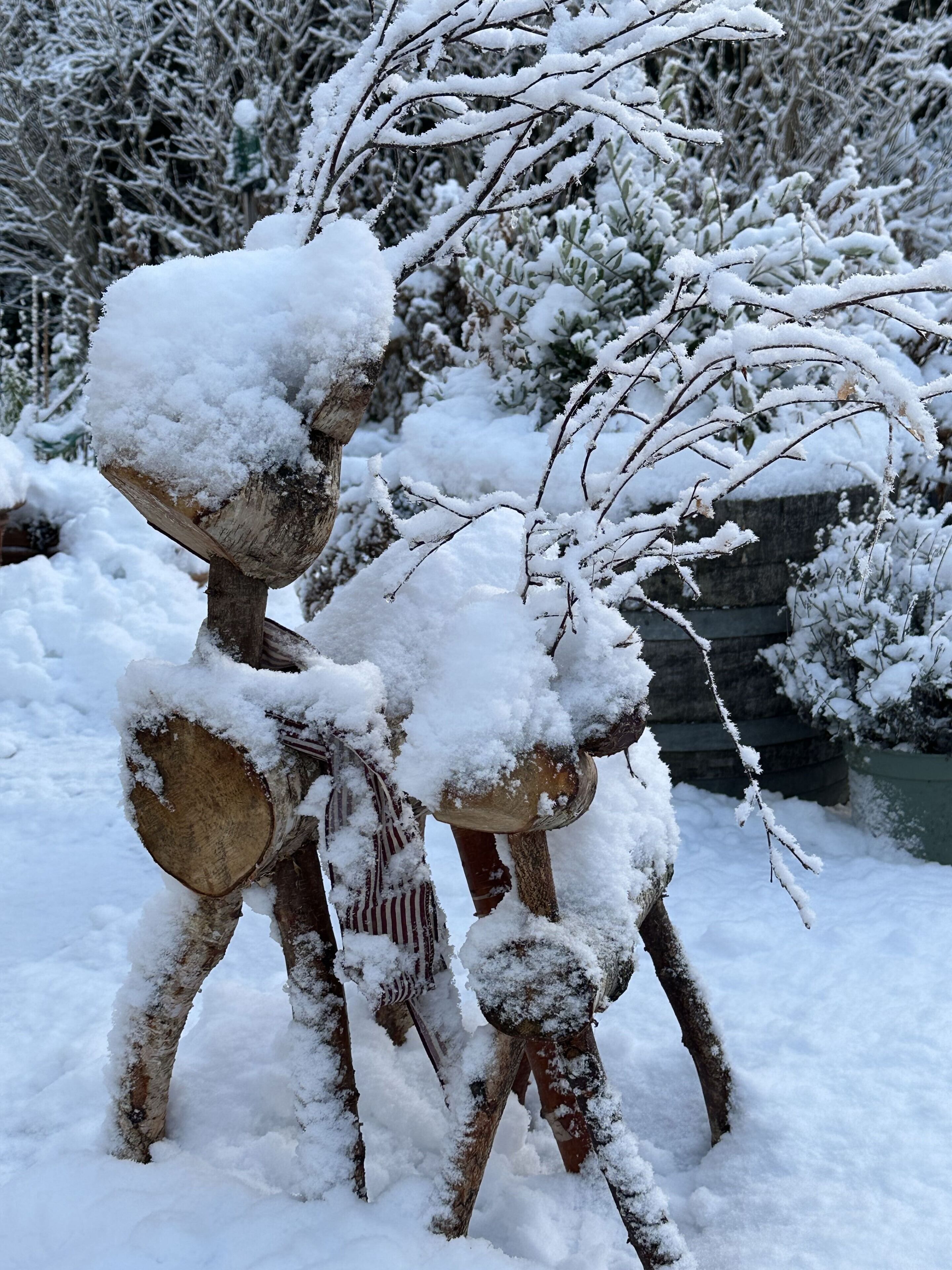 Una escultura de figura humana feta de fusta, coberta de neu, en un paisatge exterior nevós.