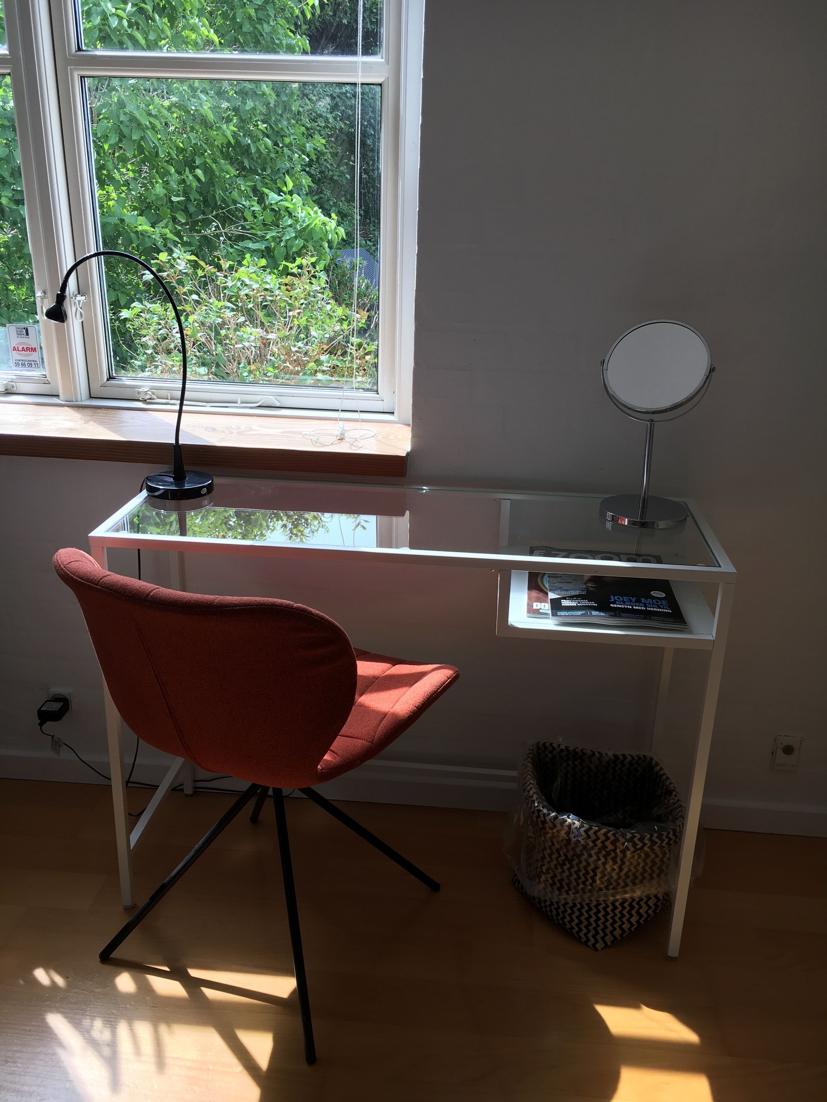 Una habitación con escritorio, silla, ventana y lámpara.